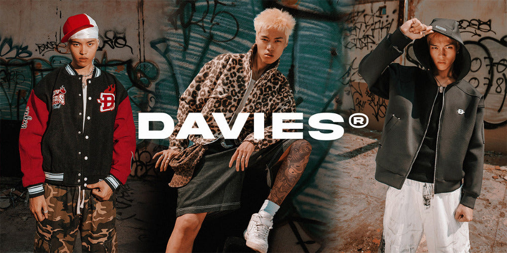 Three individuals wearing jackets with the brand 'DAVIES' logo against a graffiti-covered wall.