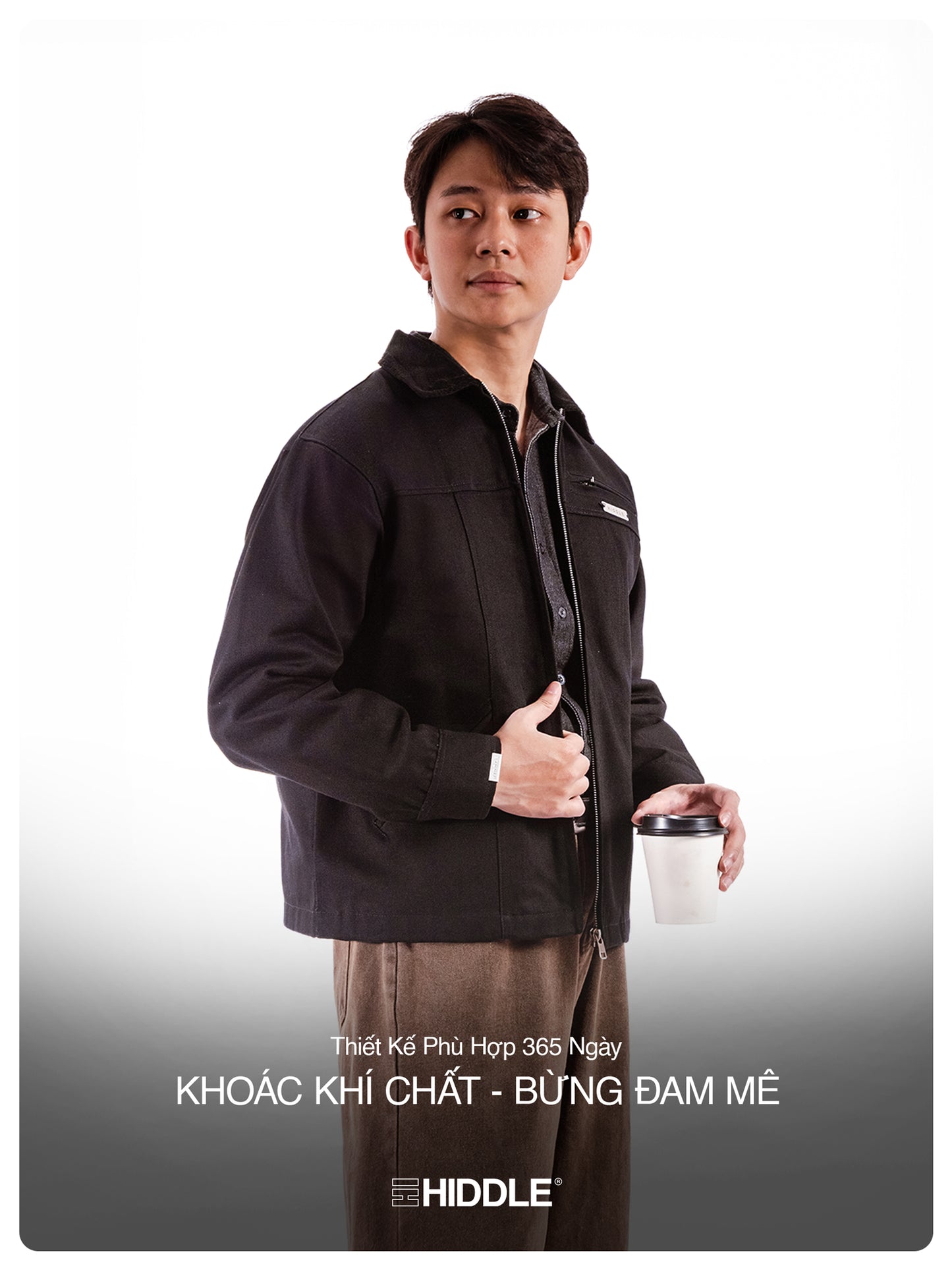 Man wearing a black jacket holding a coffee cup on a white background