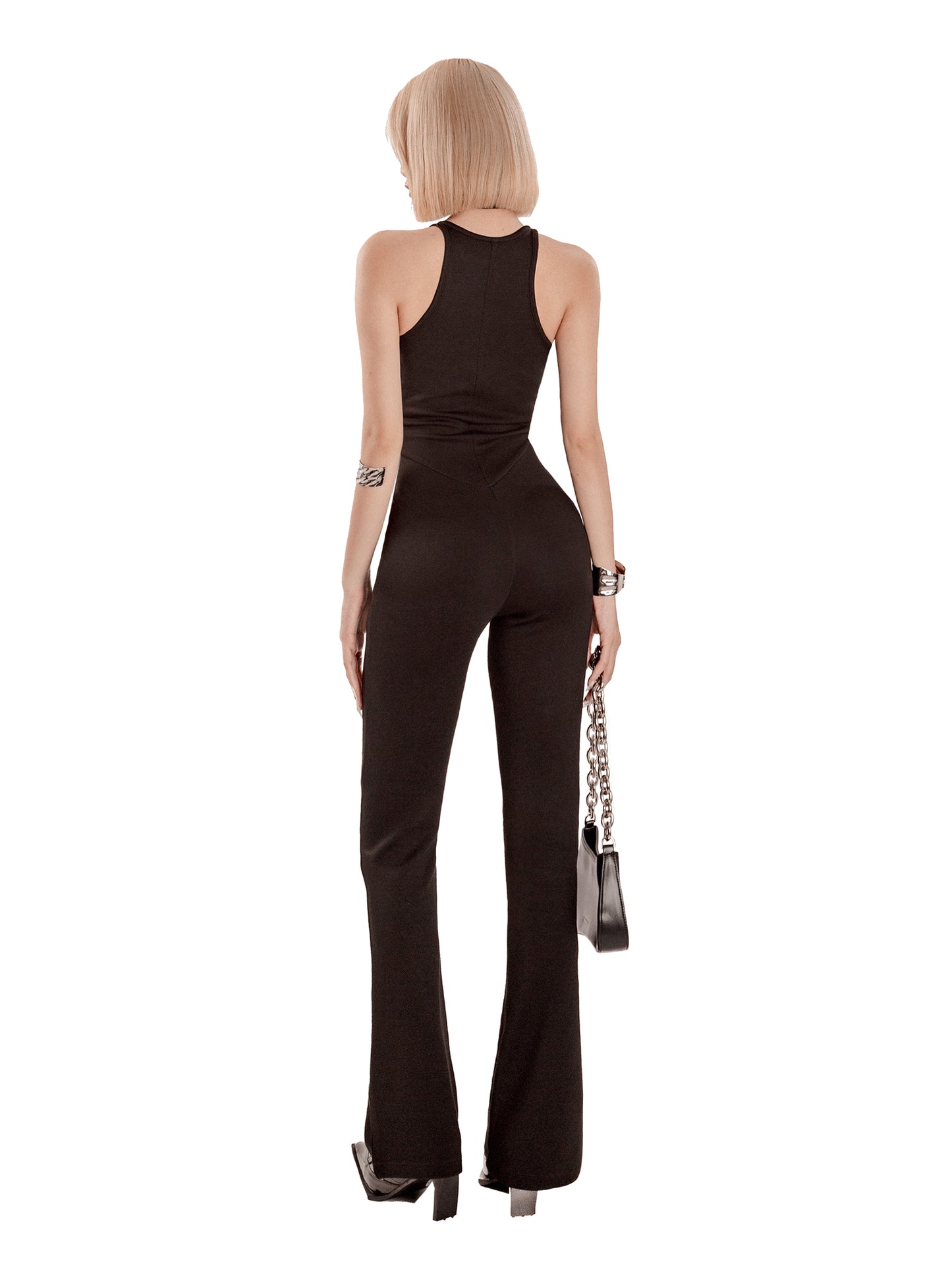 Woman wearing a black jumpsuit holding a handbag on a white background