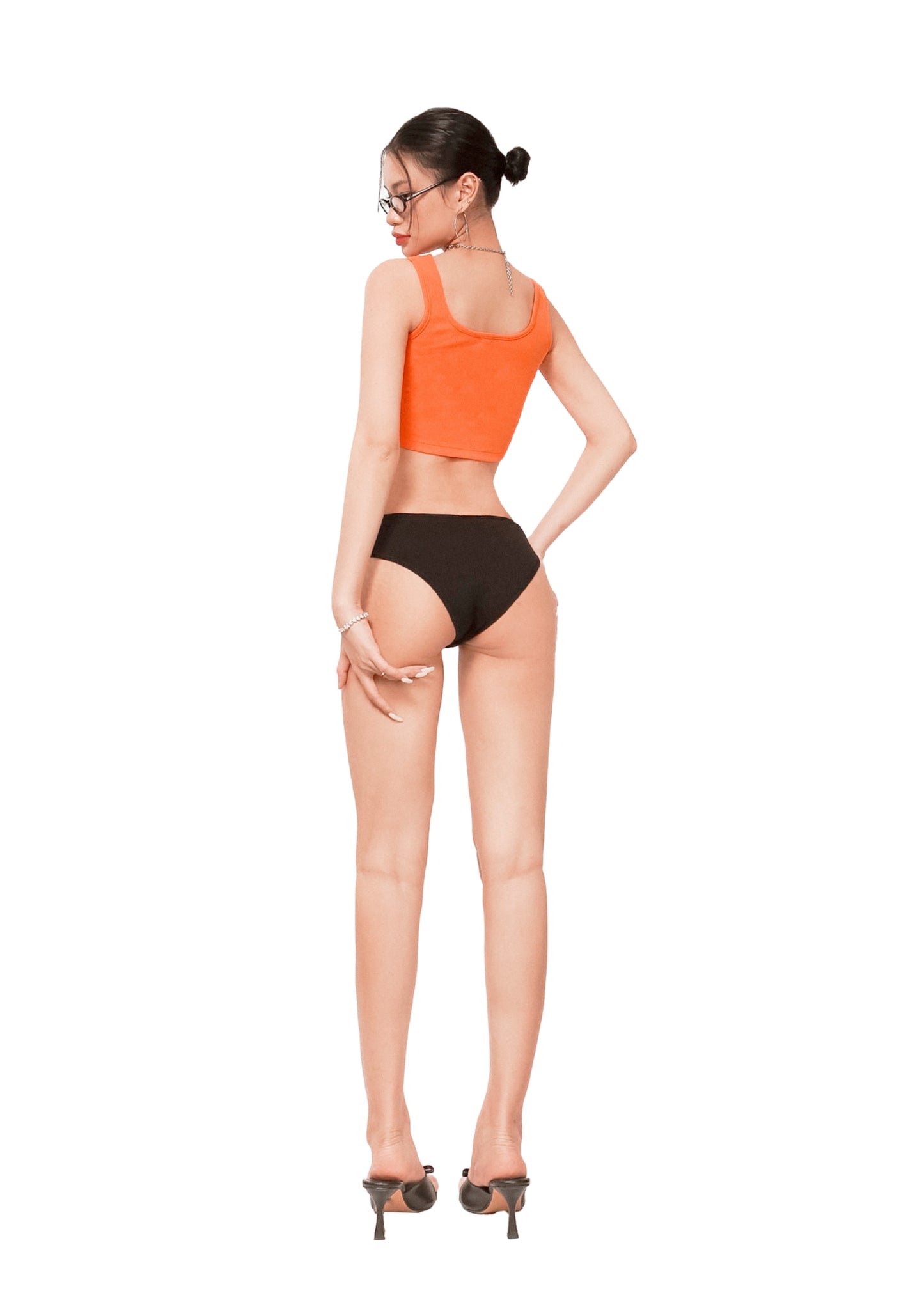 Woman wearing an orange top and black bottoms on a white background