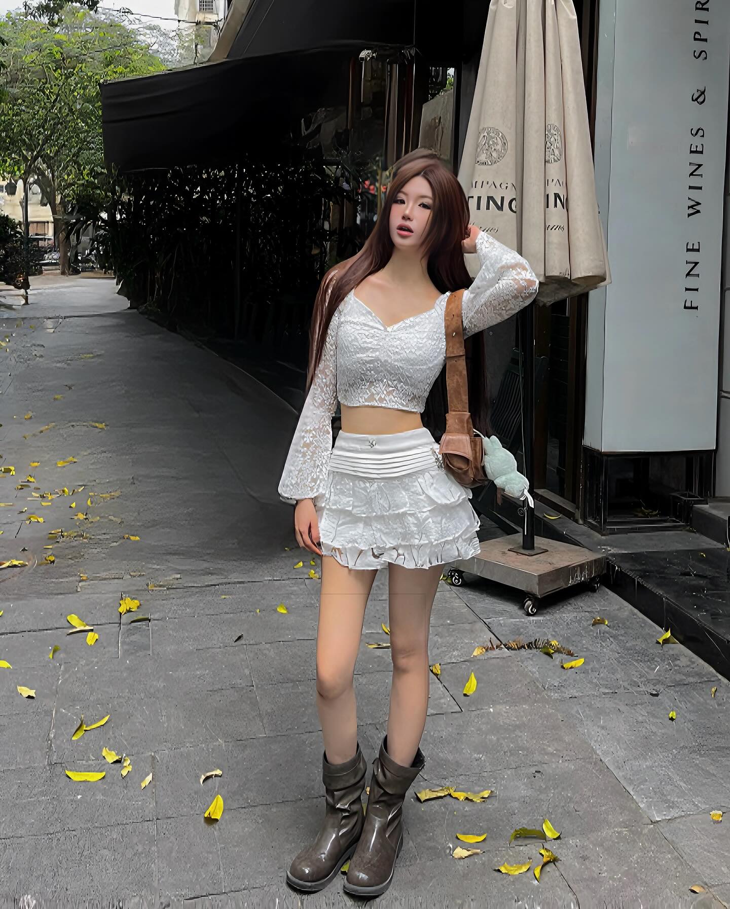 Woman in a white outfit standing on a sidewalk with a building in the background