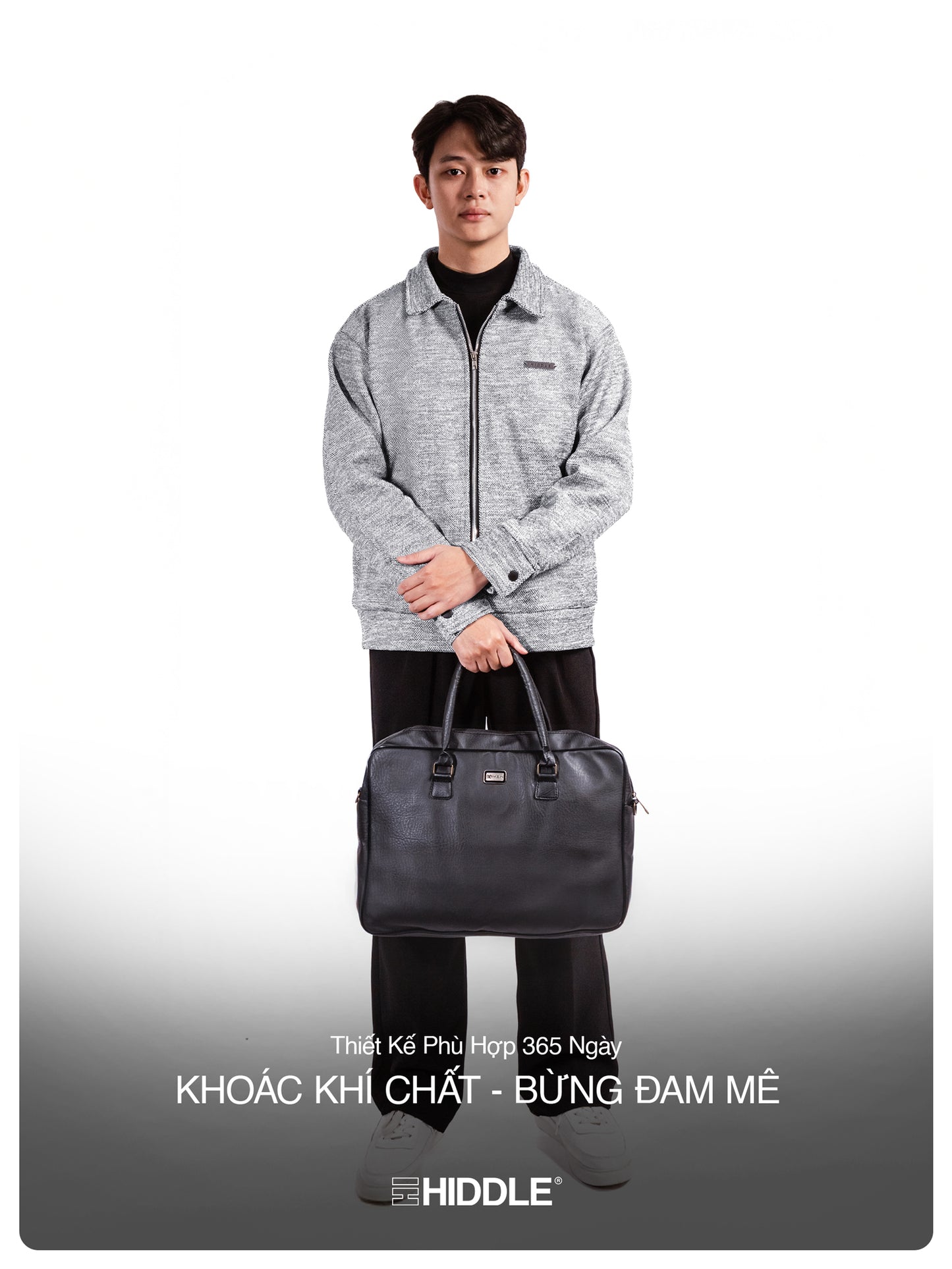 Man holding a black bag with a gray jacket on a white background