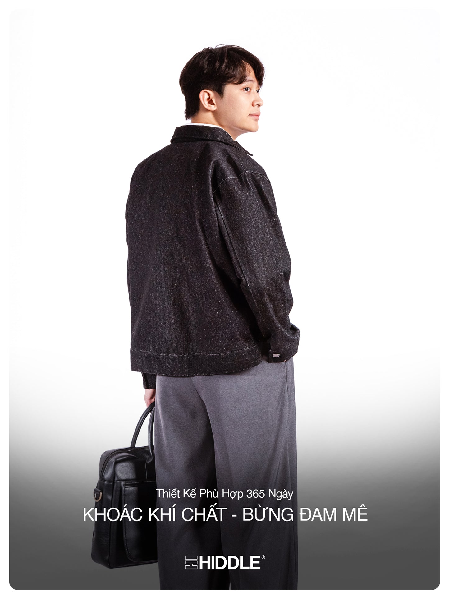 Man wearing a dark jacket and gray pants holding a black bag on a white background, with 'Hiddle' branding.