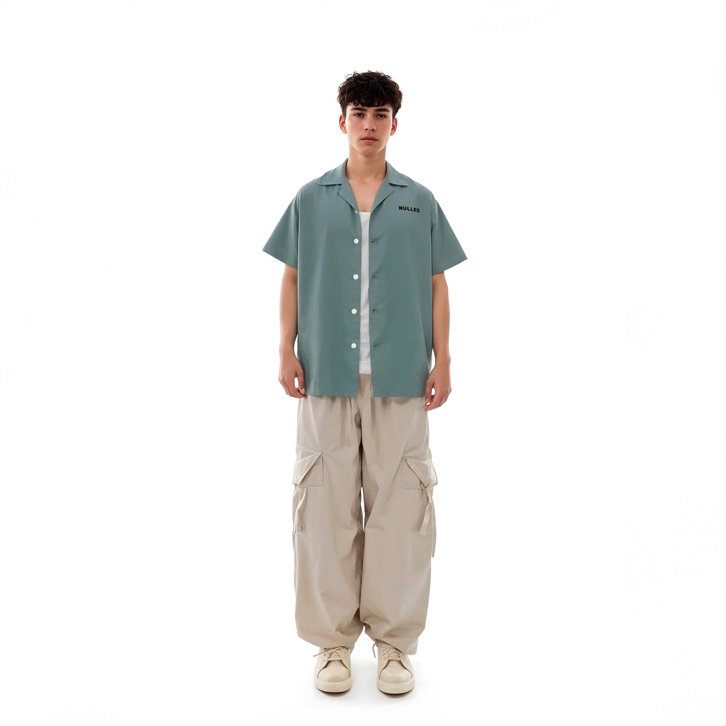 Person wearing a green shirt and beige pants on a white background