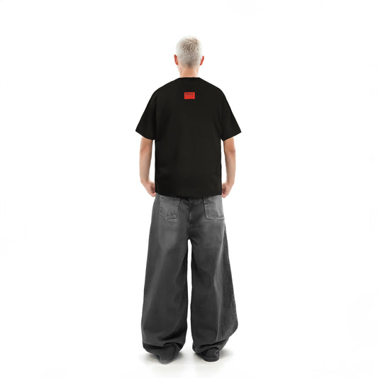 Person wearing a black t-shirt with a red logo on the back, standing against a white background