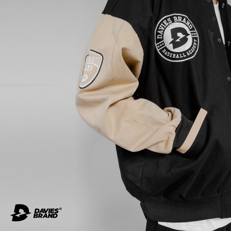 Black and beige varsity jacket with Davies Brand logo on a gray background