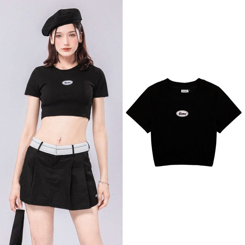 Woman wearing a black crop top with a brand logo on a gray background