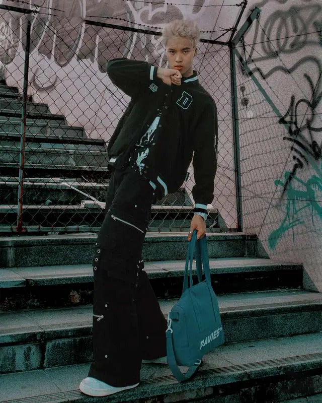 Person in black outfit holding a blue bag on graffiti-covered steps