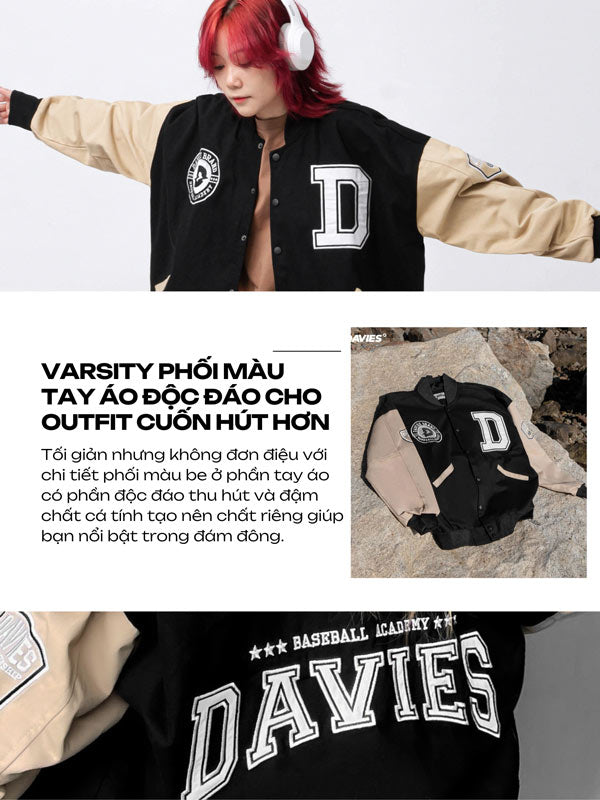Person wearing a black and beige varsity jacket with 'D' lettering, sitting on a rock.