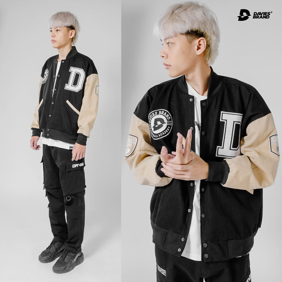 Person wearing a black and beige varsity jacket with 'Dakies Brand' logo on a white background