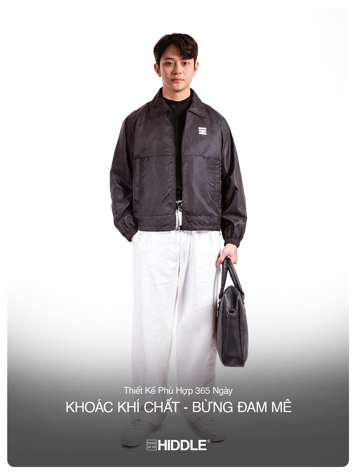 Man wearing a black jacket holding a bag on a white background with Hiddle branding.