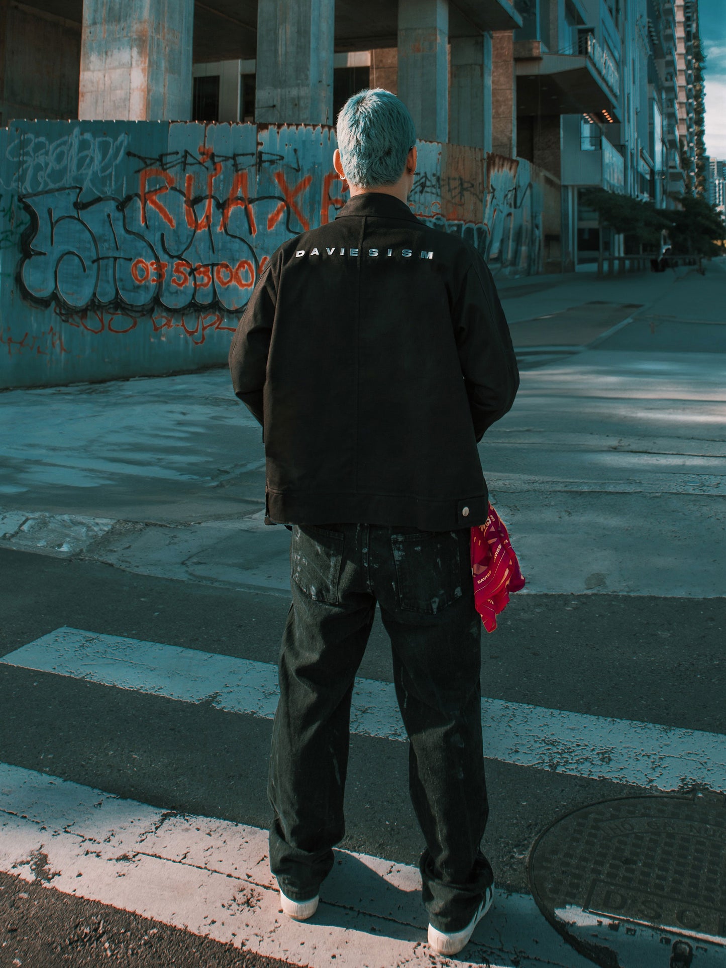 Person standing on a street with graffiti in an urban setting