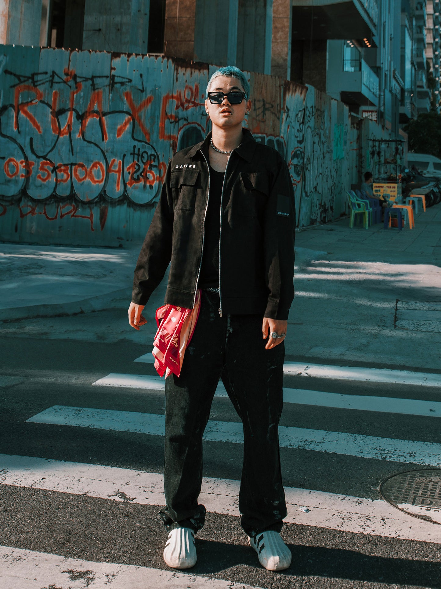 Person standing on a street with graffiti in the background