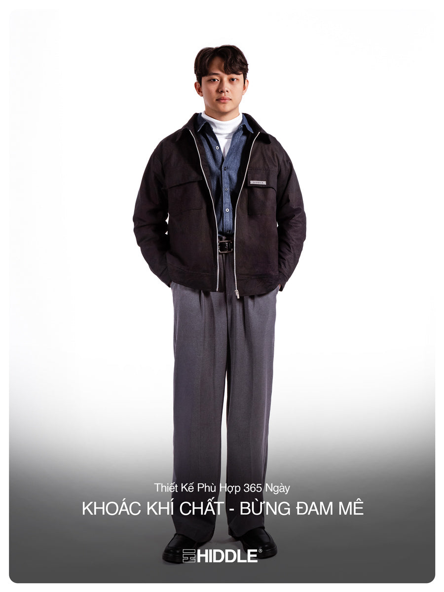 Man wearing a dark jacket and gray pants on a white background with text.