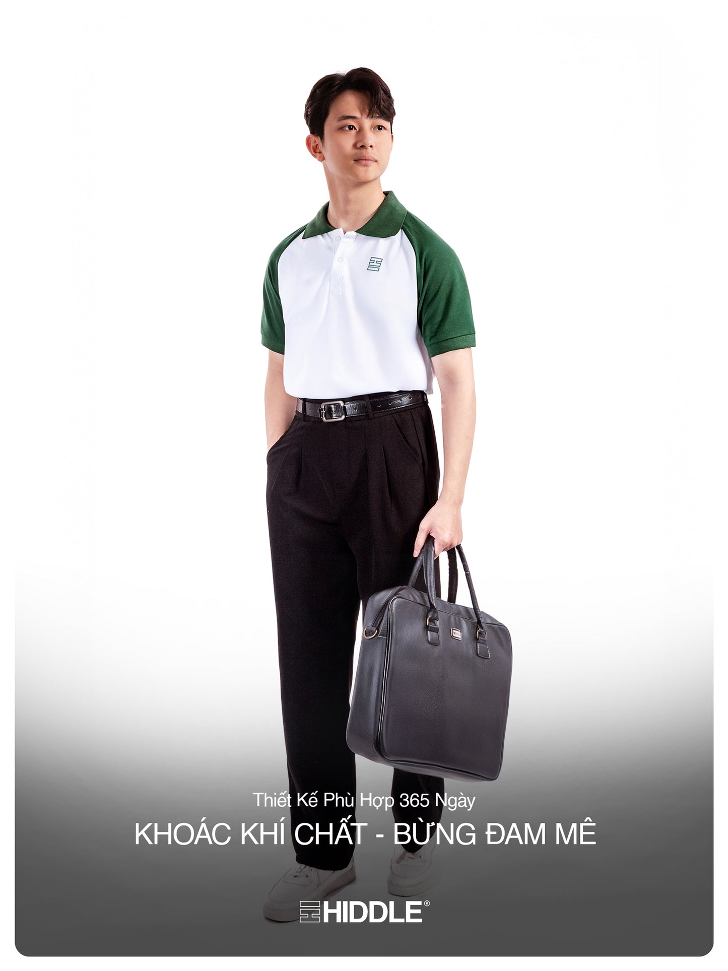 Man holding a gray bag wearing a green and white shirt with black pants on a white background