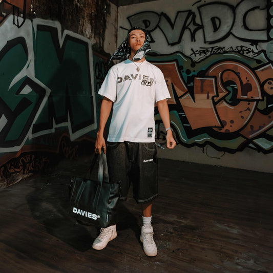 Person holding a Davies bag in front of graffiti wall