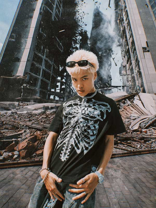 Person wearing a black t-shirt with a white graphic design in front of a destroyed building backdrop