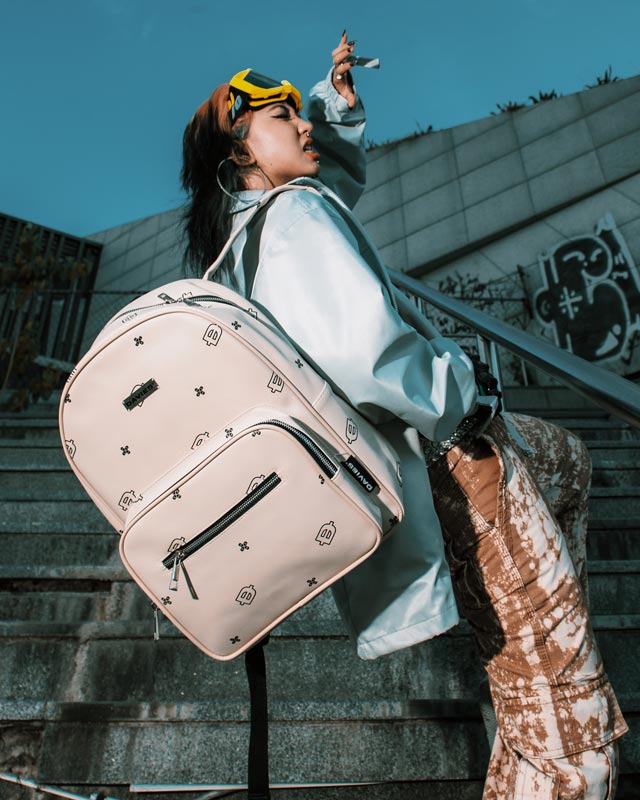 Person with a large beige backpack standing on steps outdoors