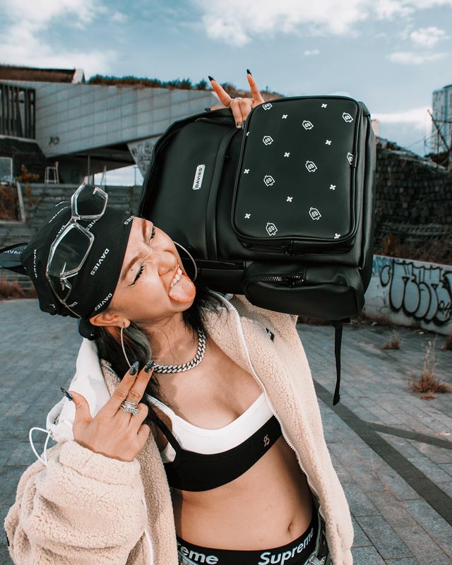 Woman holding a black backpack with white patterns against an urban background