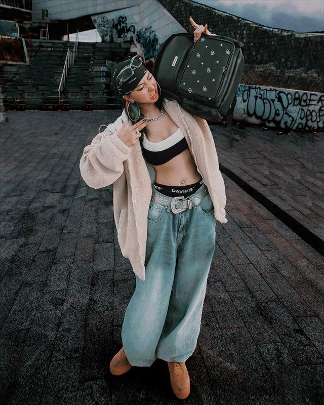 Person holding a suitcase on a rooftop with graffiti in the background