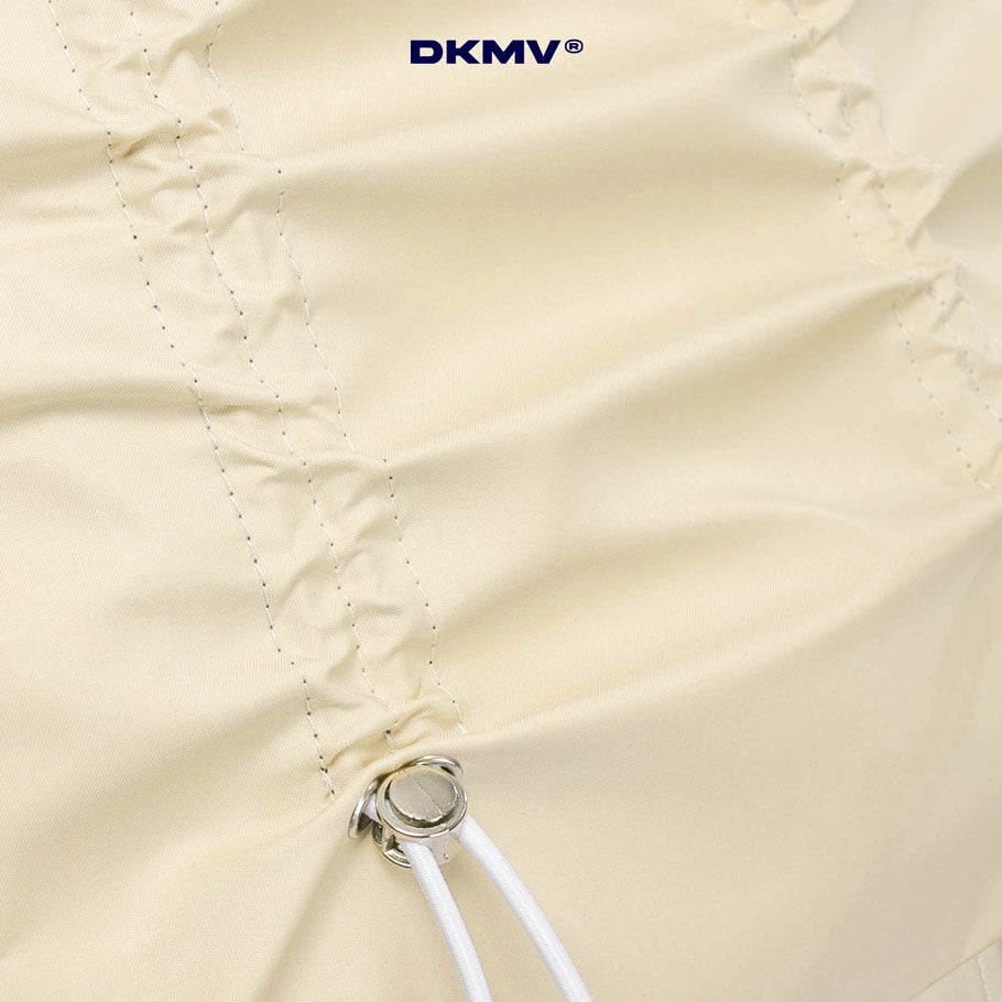 Close-up of a beige umbrella with a visible brand logo in the top right corner.