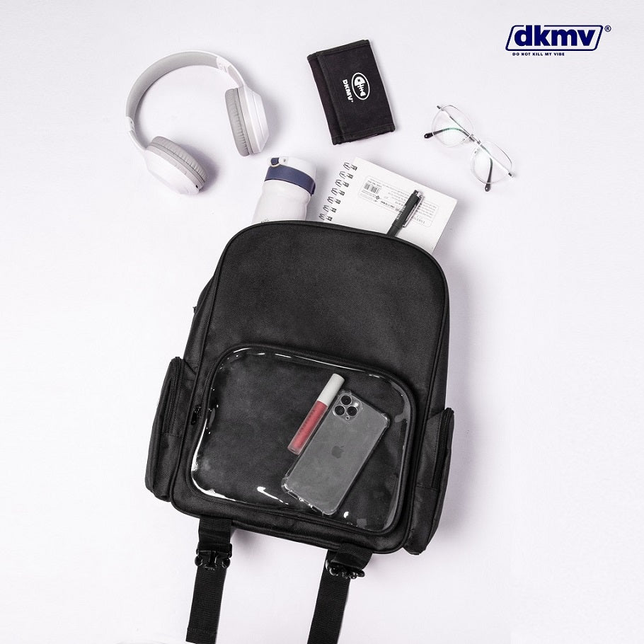 Black backpack with clear front pocket containing a phone, surrounded by earphones, notebook, and wallet on a white background with dkmv branding.