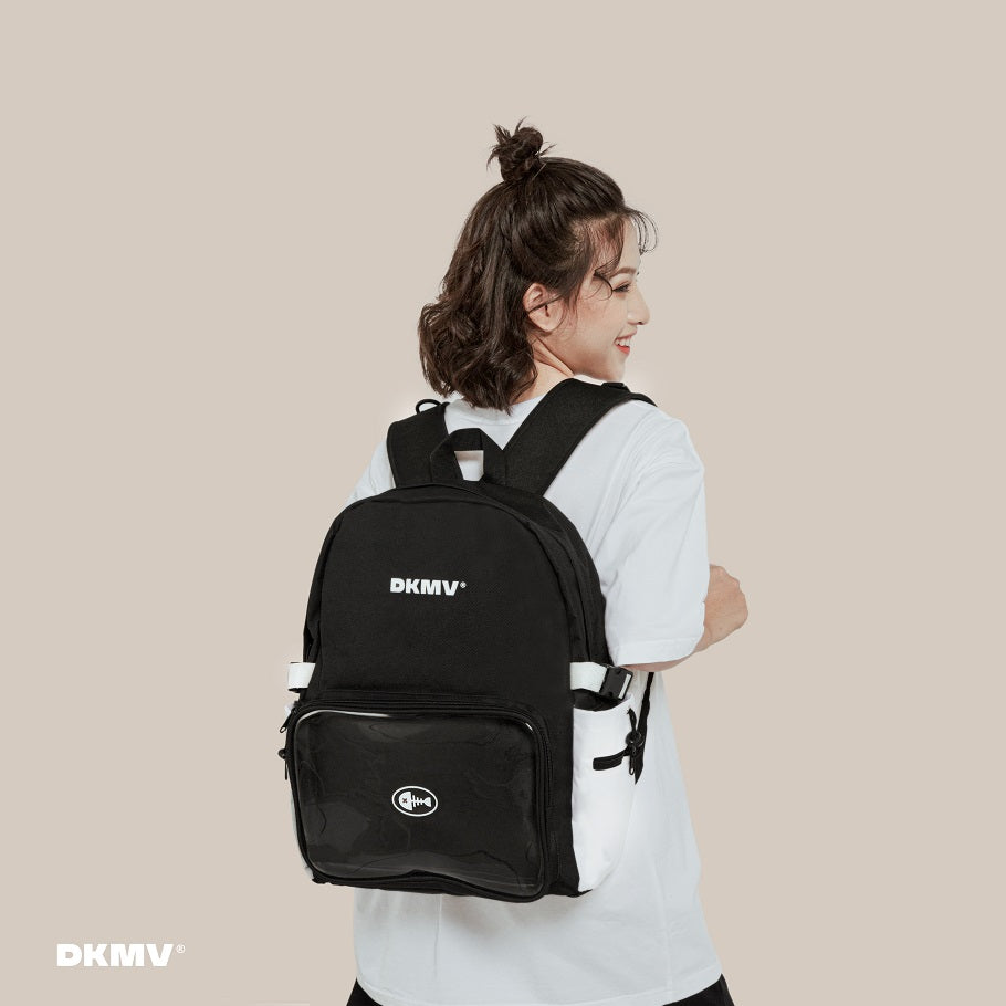 Person wearing a black backpack with 'DKMV' branding on a beige background