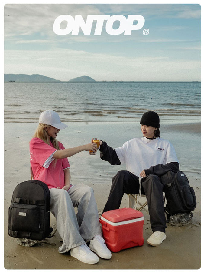 Two people sitting on a beach with a cooler and backpack, featuring the brand 'ONTOP'.