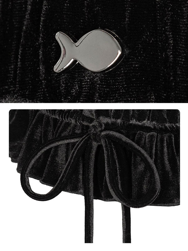 Black velvet garment with silver fish-shaped brooch on a textured black background