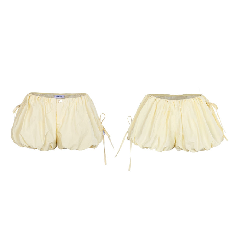 Pair of cream-colored shorts with a sheer overlay on a white background