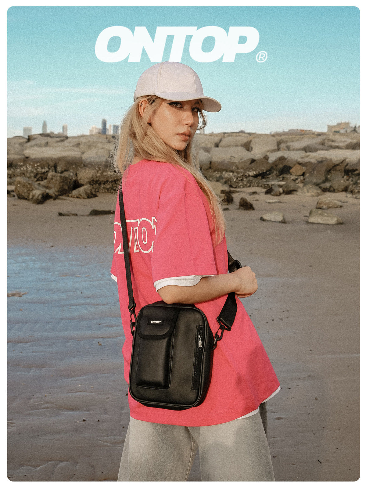 Person wearing a pink shirt with 'ONTOP' branding on a beach