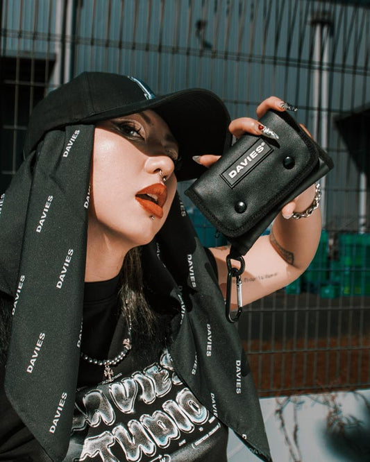 Person holding a black pouch with 'DAVIES' branding, wearing a black outfit with visible text.
