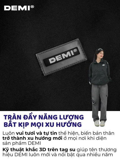 Person wearing a black jacket with a DEMI logo patch on a dark background
