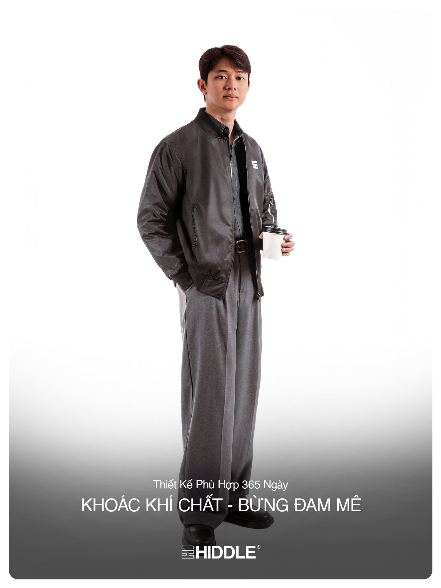Man wearing a gray outfit with a belt, holding a cup on a white background