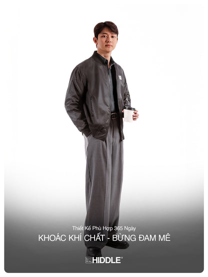 Man wearing a gray outfit with a belt, holding a cup on a white background