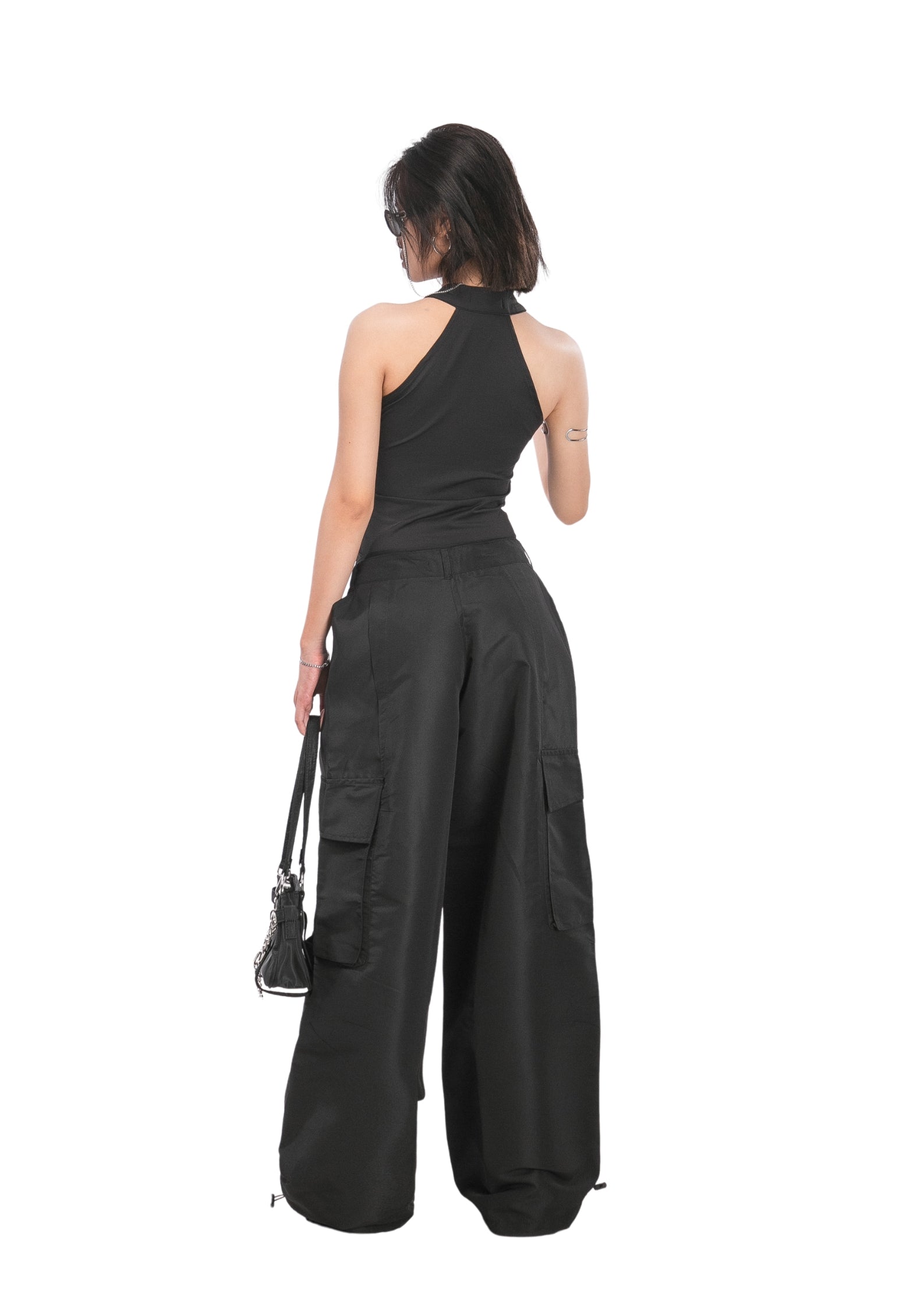 Woman wearing a black jumpsuit with wide-leg pants on a white background