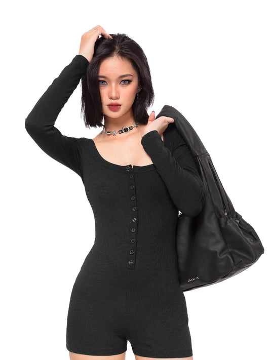 Woman wearing a black romper holding a black jacket on a white background