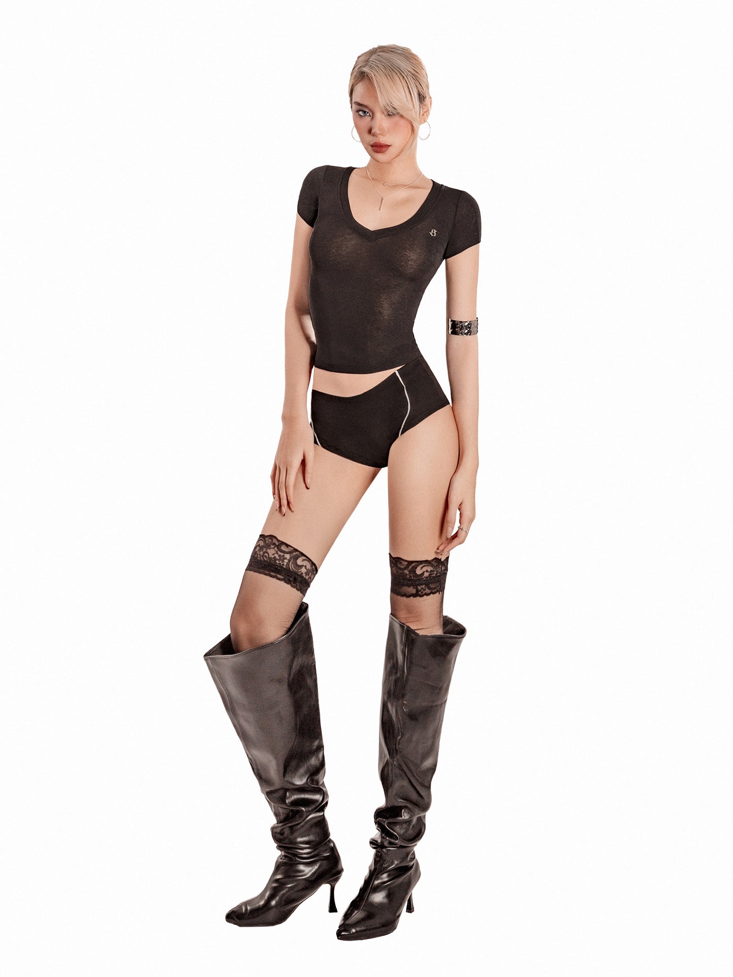 Woman wearing a black bodysuit and high boots on a white background