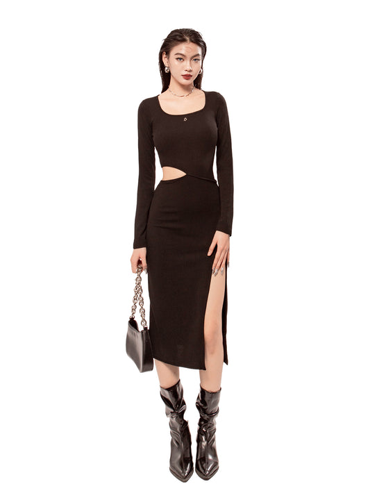 Woman wearing a black dress with cut-out design and high slit, standing against a white background.