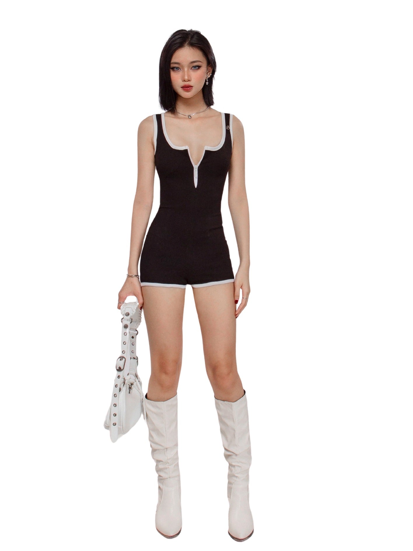 Woman wearing a black sleeveless top and shorts with white knee-high boots on a white background
