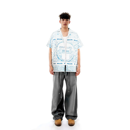 Person wearing a patterned shirt and gray pants on a white background