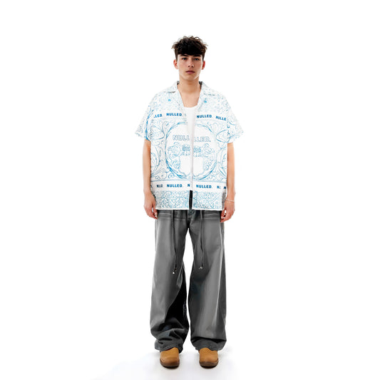 Person wearing a patterned shirt and gray pants on a white background