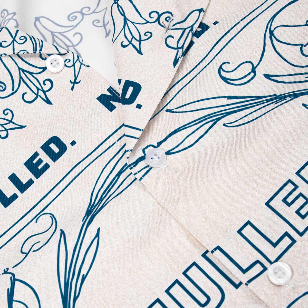 Close-up of a shirt with blue floral and text design on beige fabric.