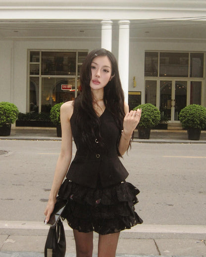 Woman in a black dress standing on a street with a building in the background