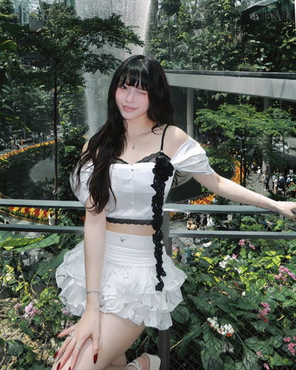 Woman in a white outfit with black accents standing in a garden setting
