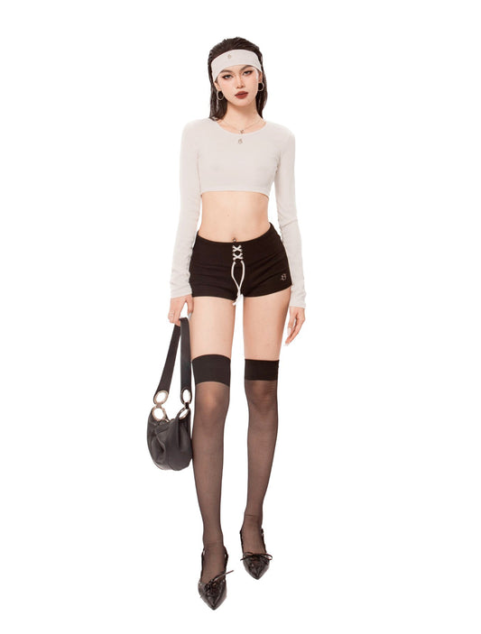 Woman wearing a white long-sleeve top, black shorts, and black stockings with a headband on a white background.