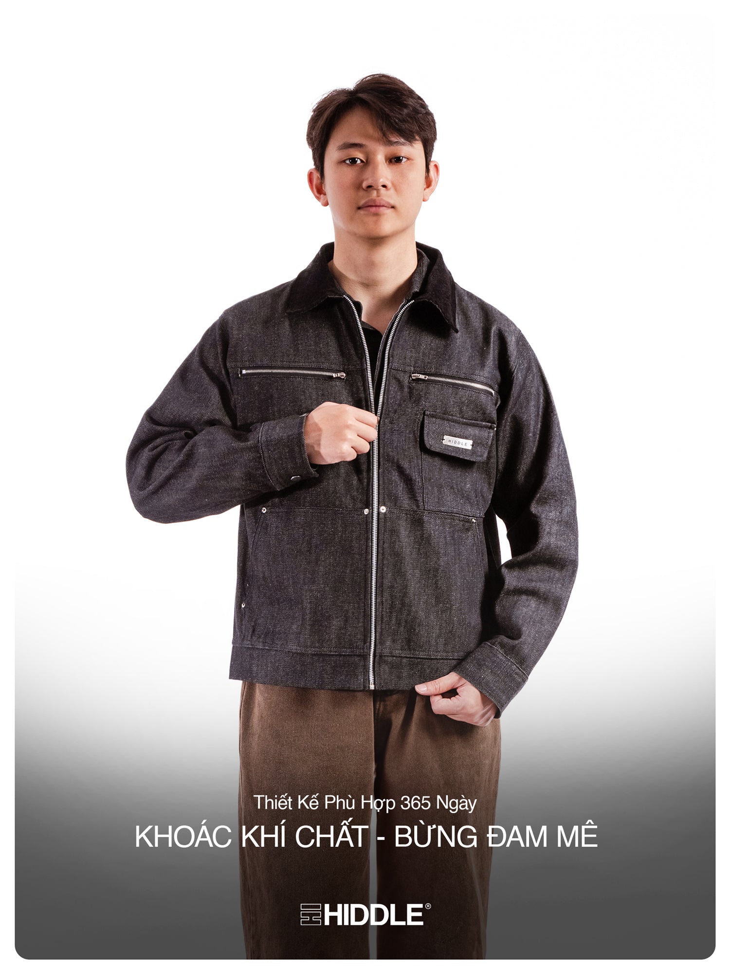 Man wearing a dark denim jacket with visible branding on a gray background