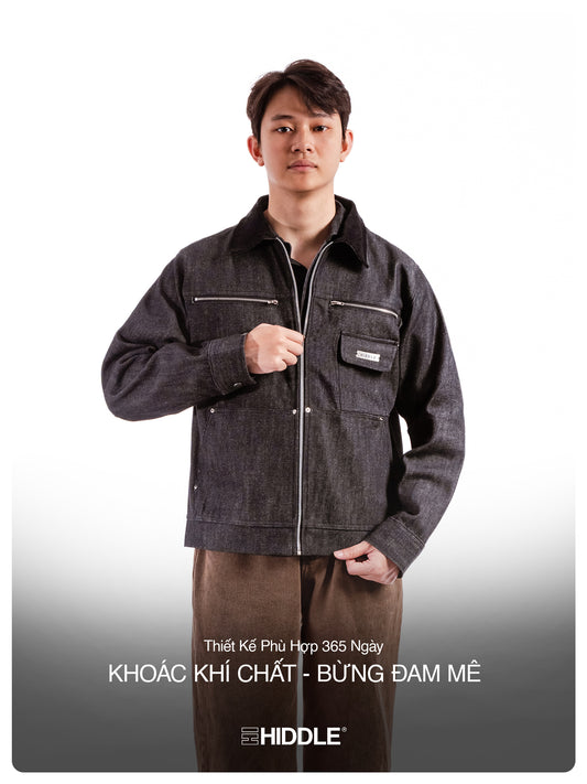 Man wearing a dark denim jacket with visible branding on a gray background