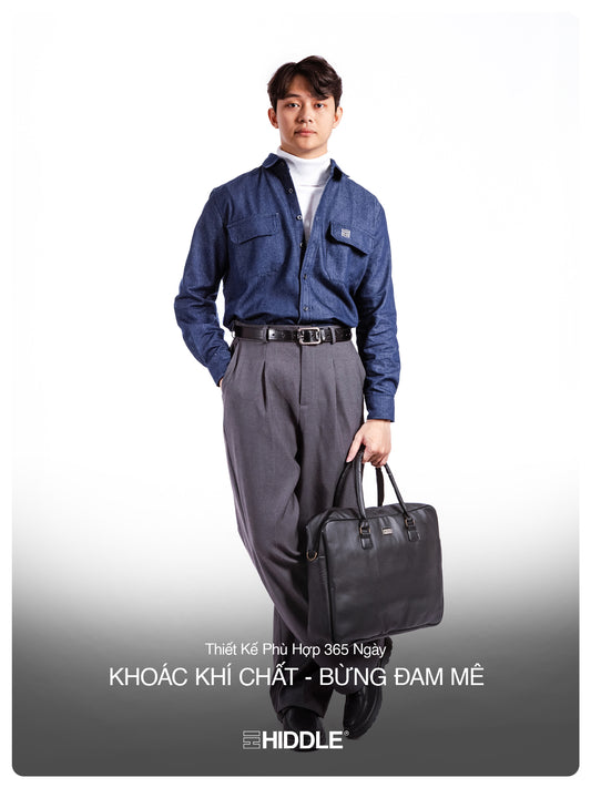 Man in blue shirt and gray pants holding a black bag on a white background