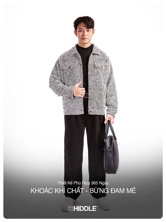 Man wearing a gray jacket and black pants holding a bag on a white background
